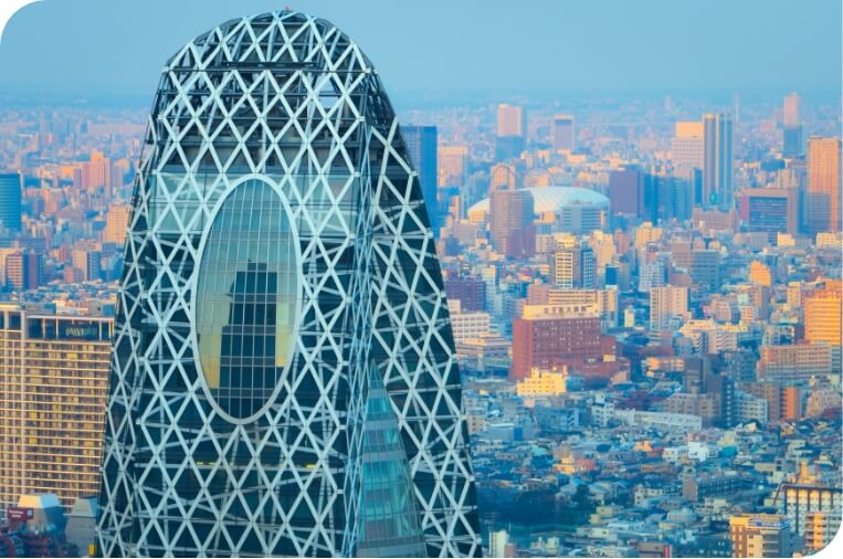 A tall, modern skyscraper with a unique oval window and a lattice-like facade, standing out against a backdrop of a sprawling cityscape.