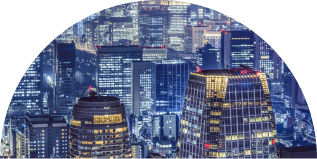 A panoramic view of a bustling city at night, with numerous skyscrapers illuminated by bright lights.